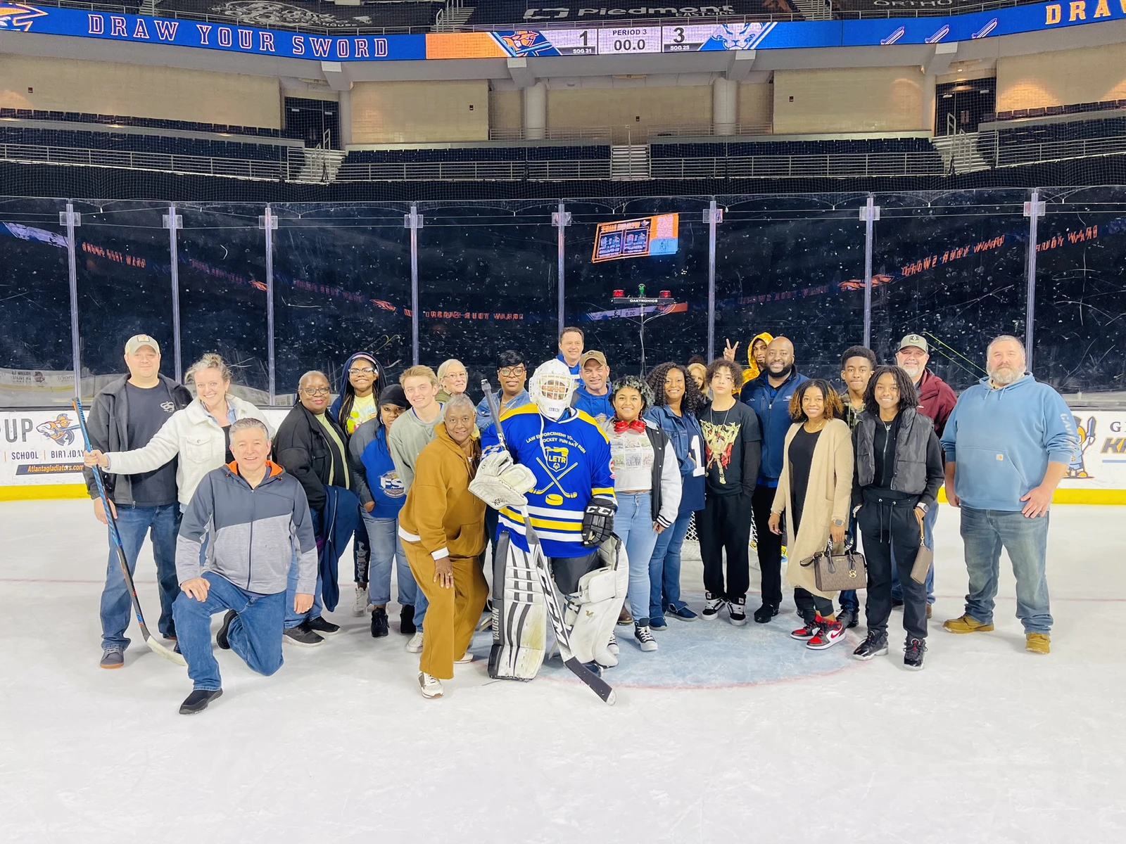 A group of people pose for a photo with a person wearing hockey gear on an ice rink inside a large arena, reminiscent of the precision and teamwork seen in fulfillment centers where every action, from picking to packing, is executed flawlessly.